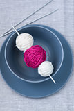 Bright balls of yarn and knitting needles on a plate