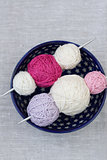 Bright balls of yarn and knitting needles on a plate
