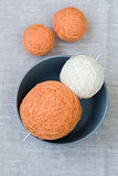 Orange and white balls of yarn and knitting needles