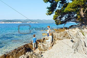 Summer stony beach and family on it (Croatia).