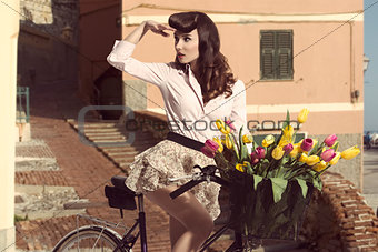 vintage pin-up with flowers on bike in old town