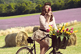 portrait of vintage pin-up on bike smelling a flower in rural co