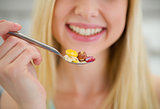 Closeup on spoon with flakes in hand of smiling teenager girl
