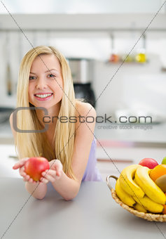 Portrait of happy teenager girl with apple in modern kitchen
