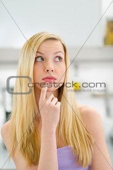 Portrait of thoughtful teenager girl in kitchen
