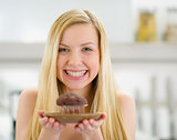 Smiling teenager girl showing chocolate muffin