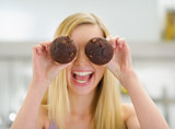 Happy teenager girl holding chocolate muffins in front of face