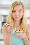 Teenager girl eating flakes with milk in kitchen