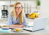 Happy teenager girl studying in kitchen