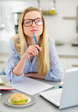 Thoughtful teenager girl studying in kitchen