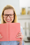 Happy teenager girl with book in kitchen