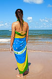 woman with the brazilian flag sarong on the beach looking at the sea