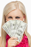 Blonde hiding her face with dollars banknotes
