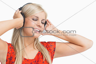 Happy blonde in orange dress listening to music
