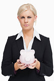 Serious businesswoman holding a piggy-bank