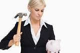 Serious businesswoman holding a piggy-bank and hammer