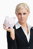 Stern businesswoman holding a piggy-bank