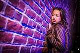 Frightened Pretty Young Woman Against Brick Wall at Night