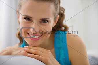 Portrait of smiling young woman sitting on couch in living room