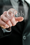Male hand pointing at Goals icon on a touch screen interface