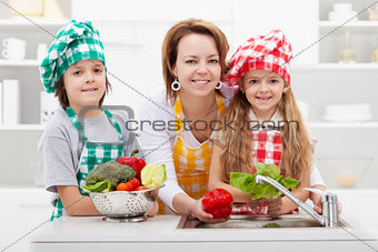 Woman washing the vegetables with the kids