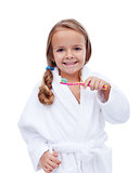 Little girl in bathrobe washing teeth