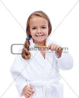 Little girl in bathrobe washing teeth