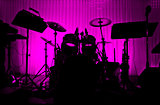 Drum in silhouette with no musician. 