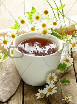 cup of tea and chamomile flowers on a wooden table