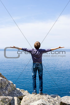 man on a mountain with open hands towards the word, blue sky end