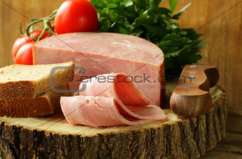 large piece of ham on a cutting board stump