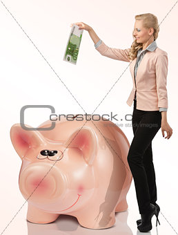 nice blond woman saving euro in a big piggy money box