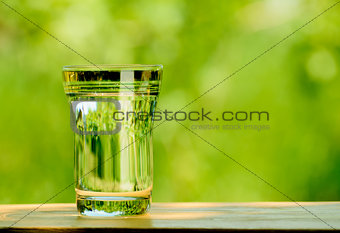 Glass Full of Water against the Green Nature Background