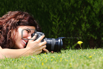 Beautiful woman taking a photography of a flower on the grass