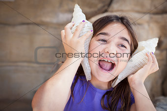 Young Girl Playing with Large Sea Shells Against Her Ears