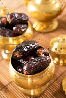 dried date fruits in golden metal bowl.