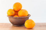 still life of oranges in a clay bowl
