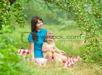 mother and daughter have picnic outdoor under apple tree branch