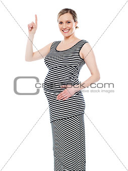 Pregnant woman pointing up at copyspace