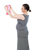 Pregnant woman looking at baby cloth, rejoicing