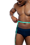 Muscular man measuring his waist