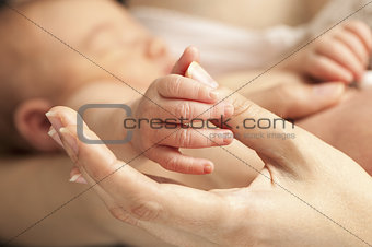 Newborn's hand holding mother's thumb