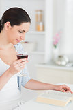 Woman reading while holding a red wine glass