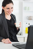 Woman holding a milk glass while looking at a laptop