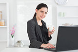 Smiling woman in front of laptop with glass of milk