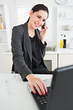 Smiling woman calling while using a laptop