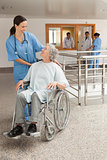 Nurse laughing with old women sitting in wheelchair