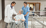 Nurse and doctor talking with old woman in wheelchair