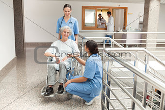 Two nurses looking after old women sitting in wheelchair