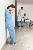 Stressed nurse leaning against wall